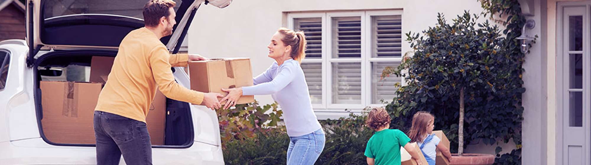 Parents moving boxes from car into their house